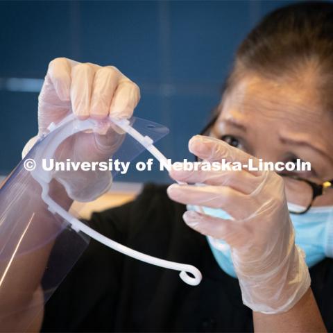 Dinning Services employees, Rochan Pinho, Janet Nichols and Dami Olsen, assemble face shields at Harper Dining Center. Once school starts up, they will use the shields for prevention of the spread of COVID-19. April 28, 2020. Photo by Gregory Nathan / University Communication.