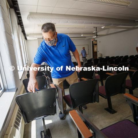 Shawn Languis, Space Planning/GIS Data Coordinator with Facilities Management and Planning, places tape on the back of a chair in an Avery Hall classrooms as they work out possibilities for 6-foot social distancing. This classroom seats 90 normally but will be reduced to 24. A group is physically measuring every classroom on campus to see if computer-aided predictions are correct. June 1, 2020. Photo by Craig Chandler / University Communication.