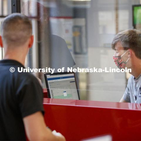 Mickey Wilson works behind a protective shield at the reception desk. First day of Campus Recreation re-opening after being shut down due to COVID-19 concerns. June 15, 2020. Photo by Craig Chandler / University Communication.