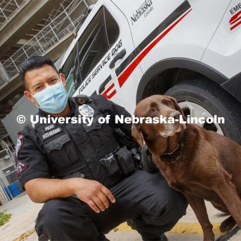 Officer Anderson Delgado, and K-9, Justice pose next to a cruiser. Officer Delgado is wearing a mask for protection as a result of the COVID-19 pandemic. UNL Police Department. June 23, 2020. Photo by Craig Chandler / University Communication.