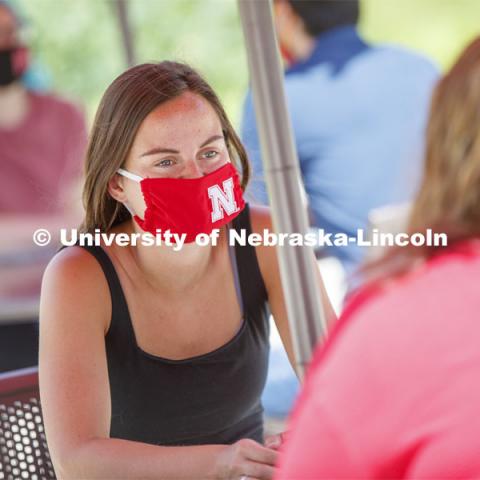 Students socialize on the patio outside the Willa Cather Dining Complex. Photo shoot of students wearing masks and practicing social distancing in dining services in Willa Cather Dining Center. July 1, 2020. Photo by Craig Chandler / University Communication.