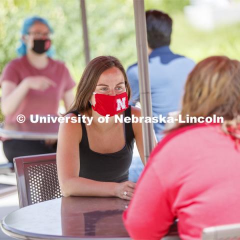 Students socialize on the patio outside the Willa Cather Dining Complex. Photo shoot of students wearing masks and practicing social distancing in dining services in Willa Cather Dining Center. July 1, 2020. Photo by Craig Chandler / University Communication.