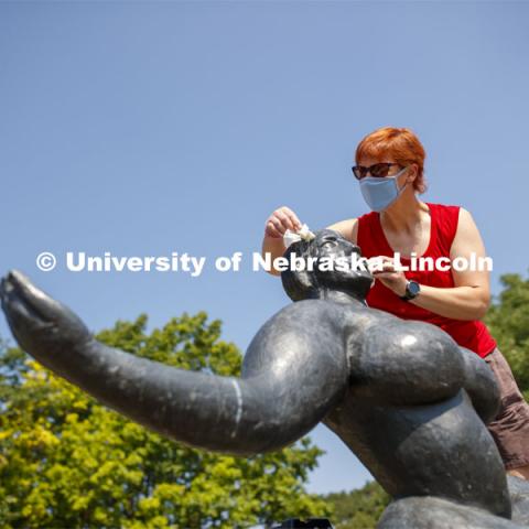 Stacey Walsh, the Sheldon Museum of Associate Registrar for Collections and Exhibitions, rids Floating Figure, a sculpture by Gaston Lachaise, of avian art critic reviews. Walsh was getting the sculpture ready for a photo shoot featuring UNL campus sculptures wearing masks. Mask wearing statues on campus. July 6, 2020. Photo by Craig Chandler / University Communication.