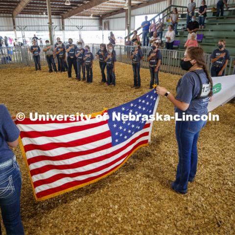 Participants in the sheep show at the Platte County Fair in Columbus, NE, pledge allegiance to the flag before the start of the show. The fair changed this year because of COVOD-19. Each livestock/animal show is a “show and go” format where 4-H'ers don't stay in the livestock barns as is tradition but transport their animals on the day of the show and work out their livestock trailers. Participants must wear a mask in the show ring. July 10, 2020. Photo by Craig Chandler / University Communication.