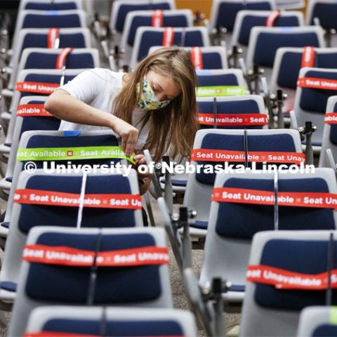 Maddie Huppert, student worker for the Executive Vice Chancellor’s office, wraps an available seat in Louise Pound Hall lecture hall with a band. The bands are flexible, so they do not need to be removed when the student sits down. Crews are marking classroom seats in Louise Pound Hall as part of preparing the campus for Forward to Fall. A crew is going room-to-room marking the where to sit and where the chairs/tables go. By Friday, they hope to have 483 classrooms and 8970 seats on all campuses marked and ready. August 3, 2020. Photo by Craig Chandler / University Communication.