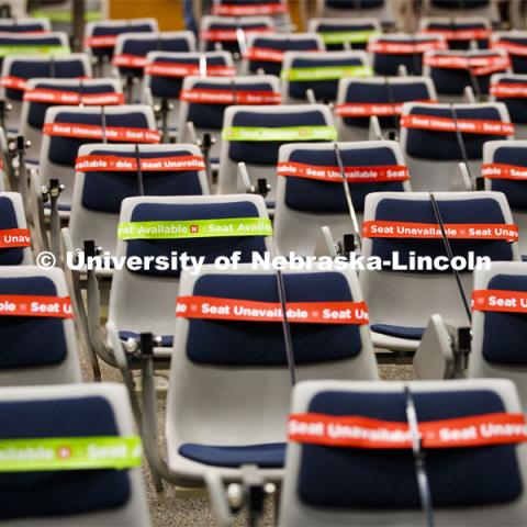 The marking crew works through the Louise Pound Hall lecture hall marking available and unavailable seats. The bands are flexible, so they do not need to be removed when the student sits down. Crews are marking classroom seats in Louise Pound Hall as part of preparing the campus for Forward to Fall. A crew is going room-to-room marking the where to sit and where the chairs/tables go. By Friday, they hope to have 483 classrooms and 8970 seats on all campuses marked and ready. August 3, 2020. Photo by Craig Chandler / University Communication.