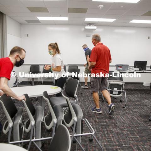 Extra chairs are moved out from a classroom in Louise Pound Hall. Crews are arking classroom seats in Louise Pound Hall as part of preparing the campus for Forward to Fall. A crew is going room-to-room marking the where to sit and where the chairs/tables go. By Friday, they hope to have 483 classrooms and 8970 seats on all campuses marked and ready. August 3, 2020. Photo by Craig Chandler / University Communication.