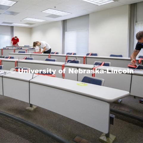 Crews marking classroom seats in Louise Pound Hall as part of preparing the campus for Forward to Fall. A crew is going room-to-room marking the where to sit and where the chairs/tables go. By Friday, they hope to have 483 classrooms and 8970 seats on all campuses marked and ready. August 3, 2020. Photo by Craig Chandler / University Communication.