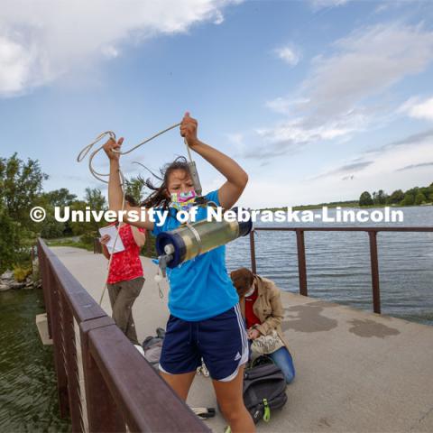 Malayna Wingert, a sophomore from Sterling, NE, lifts a water sample out of Holmes Lake as Anni Poetz and Maddie Carpenter record data. UCARE students of Professor Jessica Corman take water samples at Holmes Lake. The project is to see what makes the local lakes turn green. Is it an influx of nutrients from rain? Warm weather in the summer? They are testing what nutrients promote growth of algae and cyanobacteria in the lake, and they are testing this throughout the year. August 10, 2020. Photo by Craig Chandler / University Communication.