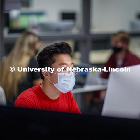 A masked student works on a computer in Anderson Hall. Photo shoot of students wearing masks and practicing social distancing. August 11, 2020 Photo by Craig Chandler / University Communication.