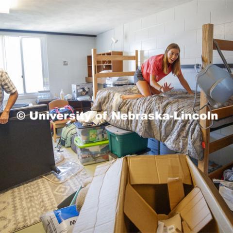Kailey Trampe of Axtell, NE, smiles for her mom, Sara, as she makes her bed. Kailey's dad, Todd, works on assembling the futon. First day of residence hall move in. August 13, 2020. Photo by Craig Chandler / University Communication.