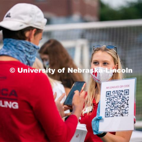 A Nebraska Campus Recreation employee (right) holds up a QR code for students to scan during the HuskerMania Masker Singer event at Mabel Lee Fields. August 21, 2020. Photo by Jordan Opp for University Communication.