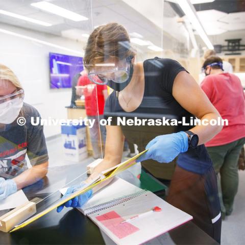 Johanna Ilves, right, and Clarissa Marron work on the report as the two lab partners are separated by an acrylic barrier in the Chemistry 105 lab. First day for in-person learning for the fall semester. August 24, 2020. Photo by Craig Chandler / University Communication.