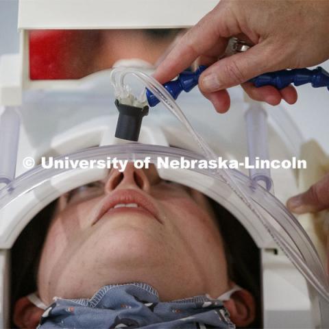 The milkshake mouthpiece is adjusted down to the patients mouth as she lies on the MRI bed. Nebraska’s Tim Nelson has received a new five-year grant to extend research into obesity. One component of it is to test subjects at the Center for Brain, Biology and Behavior by having the test subject in an MRI receiving sips of milkshakes. September 1, 2020. Photo by Craig Chandler / University Communication.