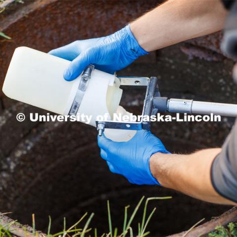 Spencer Perry, graduate student in environmental engineering, takes a wastewater sample from the sewer flowing from Harper Residence Hall. He and Shannon Bartelt-Hunt, professor in civil engineering, are sampling wastewater from UNL residence halls for COVID research. September 24, 2020. Photo by Craig Chandler / University Communication.