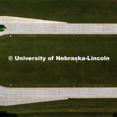 A tractor pulls the test car (yellow) and an additional tractor for weight as it rounds the test track on east campus. The University of Nebraska Tractor Test Laboratory (NTTL) is the officially designated tractor testing station for the United States. It has operated for more than 100 years. East Campus. September 28, 2020. Photo by Craig Chandler / University Communication.