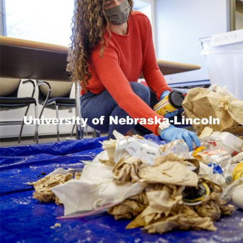 Morgan Hartman sorts waste in an Andersen Hall classroom. The waste audit was performed on trash saved by the custodians in Andersen Hall. After spreading out a tarp to sort the trash on, the bag is weighed and then dumped for sorting. Of the 11.9 pounds of trash in this bag, 38% was landfill material, 48% was compostable and 14% was recyclable. October 26, 2020. Photo by Craig Chandler / University Communication.