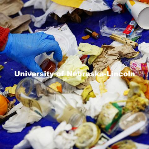 Morgan Hartman sorts through the trash. The waste audit was performed on trash saved by the custodians in Andersen Hall. After spreading out a tarp to sort the trash on, the bag is weighed and then dumped for sorting. Of the 11.9 pounds of trash in this bag, 38% was landfill material, 48% was compostable and 14% was recyclable. October 26, 2020. Photo by Craig Chandler / University Communication.