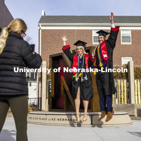 Paige Heitkamp, a senior in Criminal Justice from Sioux Falls, SD, and Tucker Thompson, a senior in secondary education from Highland Park, Illinois, jump for joy as they are photographed by Jessica Kistaitis in front of The Value of N sculpture at the alumni center. December 8, 2020. Photo by Craig Chandler / University Communication.