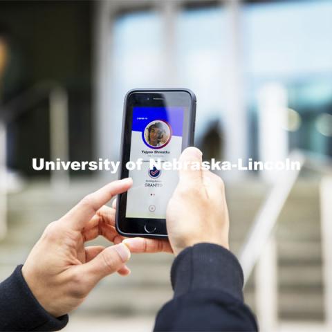 Yajyoo Shrestha shows the Safer Community app to be used as part of COVID testing on campus this spring.  Phone screen is simulated and may change slightly in the final rollout. January 8, 2021. Photo by Craig Chandler / University Communication.