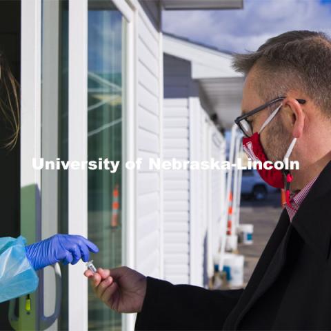 Chancellor Ronnie Green gives his saliva sample to Kaitlin Cartwright. Chancellor Green spoke with media before taking his COVID-19 saliva test Tuesday afternoon at the East Stadium loop site.  January 19, 2021. Photo by Craig Chandler / University Communication