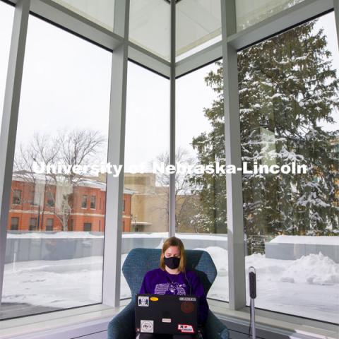 Lydia Cole, a senior from Plattsmouth, NE, studies in the corner seat ner the windows of the Dinsdale Family Learning Commons on East Campus. January 28, 2021. Photo by Craig Chandler / University Communication.