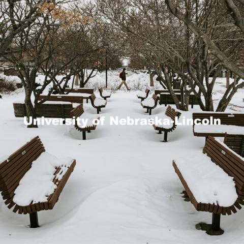 The benches and picnic tables in the green space between the Lied and the Sheldon Sculpture Gardens is covered in snow. Snow on city campus. February 10, 2021. Photo by Craig Chandler / University Communication