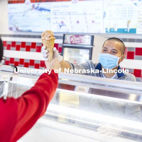 Duy Nguyen serves up a cone of his favorite flavor, Butterscotch Frost. Duy Nguyen is the manager of the Dairy Store. February 26, 2021. Photo by Craig Chandler / University Communication.