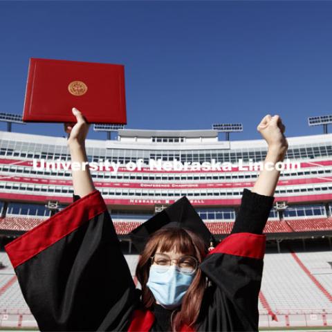 Macy Behrens, senior in advertising and public relations and also graphic design, poses in regalia to announce spring commencement will be in Memorial Stadium. March 1, 2021. Photo by Craig Chandler / University Communication.