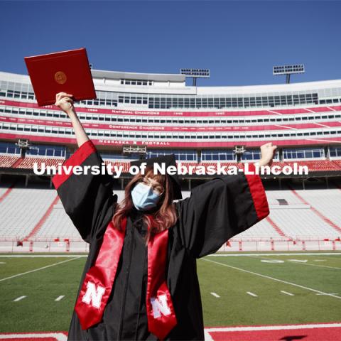 Macy Behrens, senior in advertising and public relations and also graphic design, poses in regalia to announce spring commencement will be in Memorial Stadium. March 1, 2021. Photo by Craig Chandler / University Communication.