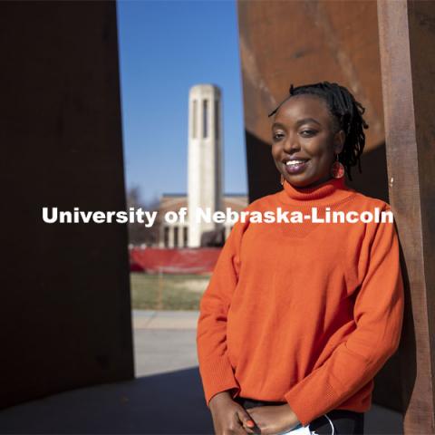 Shemsa Ndahiro Iribagiza, a senior integrated science major from Kigali, Rwanda, stands by the Greenpoint sculpture on City Campus. March 4, 2021. Photo by Craig Chandler / University Communication.