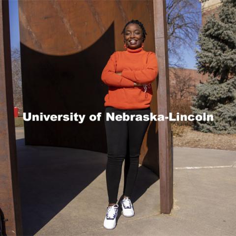 Shemsa Ndahiro Iribagiza, a senior integrated science major from Kigali, Rwanda, stands by the Greenpoint sculpture on City Campus. March 4, 2021. Photo by Craig Chandler / University Communication.