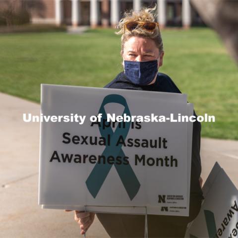 CARE Advocate Melissa Wilkerson organizes signs before placing them at the Nebraska Union Greenspace. Flags and signs are placed in the Nebraska Union Greenspace to promote Sexual Assault Awareness Month. April 4, 2021. Photo by Jordan Opp for University Communication.