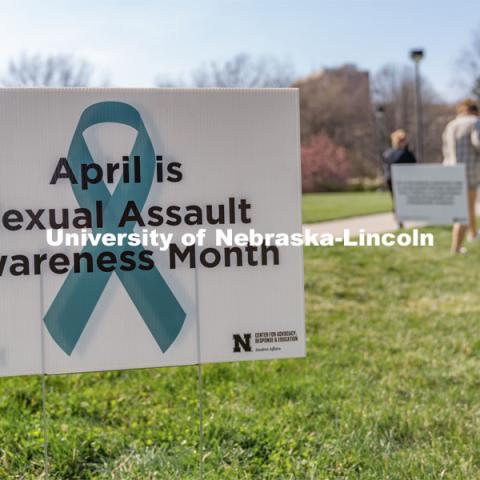 A sign recognizing April as sexual assault awareness month is placed on the Nebraska Union Greenspace. Flags and signs are placed in the Nebraska Union Greenspace to promote Sexual Assault Awareness Month. April 4, 2021. Photo by Jordan Opp for University Communication.