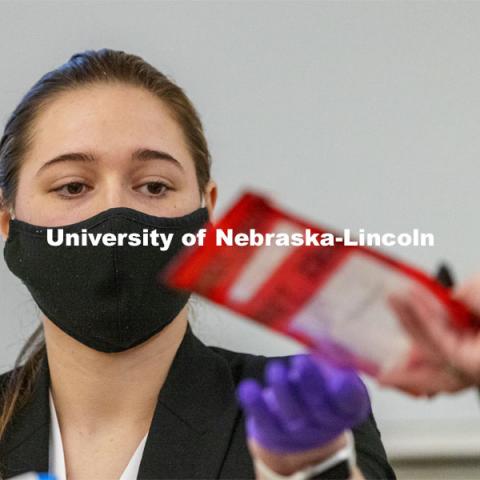 Gabby Smith is handed an evidence bag as she testifies on evidence she tested. Forensic Science 485 students give evidence in a mock trial. The course is the capstone for the seniors. The CSI option students work a mock crime scene while the biochemistry option students process the samples. April 13, 2021. Photo by Craig Chandler / University Communication.