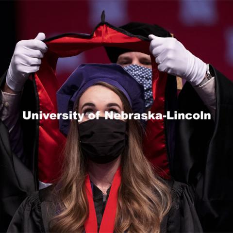 Emily Coffey eyes the prize as her doctoral hood is lowered over her head. College of Law Graduation at Pinnacle Bank Arena. May 7, 2021. Photo by Craig Chandler / University Communication.