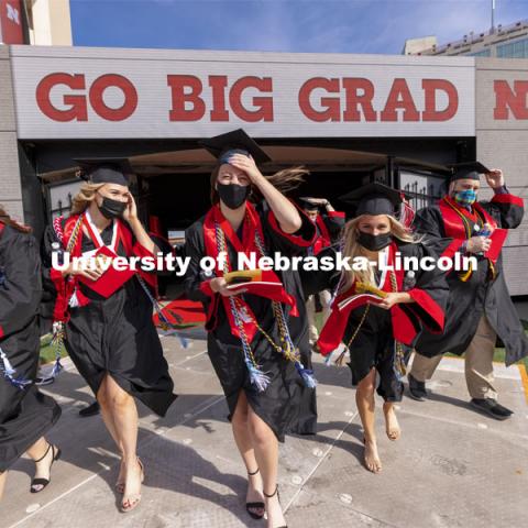 Graduates walk onto the field as they hang on to their mortar board and stoles in the brisk wind. UNL Commencement in Memorial Stadium. May 8, 2021. Photo by Craig Chandler / University Communication.