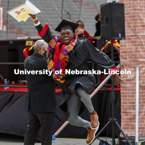 DeShawn McGary lets his graduation joy show as he walks off the ramp. McGary, who received a CoB degree, had removed his mask for his grad photo and leaped before putting it back on. UNL Commencement in Memorial Stadium.  May 8, 2021. Photo by Craig Chandler / University Communication.  