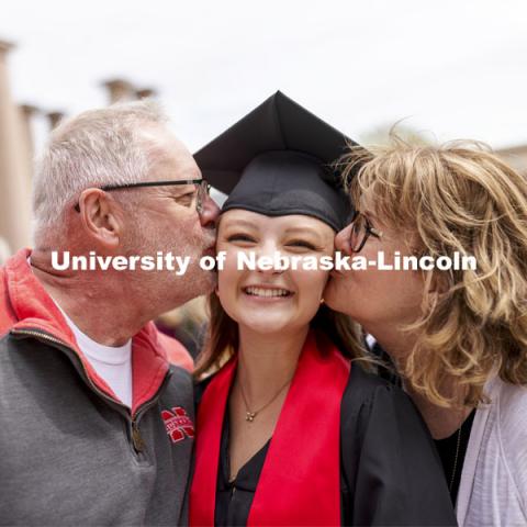 Mike and Judy Hartong kiss their daughter, Samantha, while taking photos with family and friends after the ceremony. UNL Commencement in Memorial Stadium. May 8, 2021. Photo by Craig Chandler / University Communication.