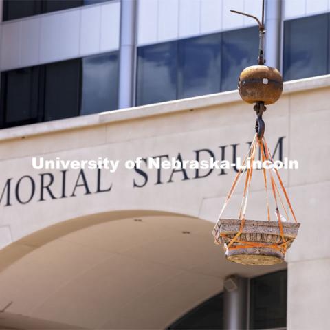 A column’s capital swings over towards its storage. The columns outside of Memorial Stadium are being removed to make way for the new athletics complex. They are being stored until a new site is developed on campus. May 12, 2021. Photo by Craig Chandler / University Communication.