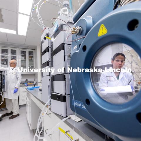 Lab Manager Anne Fischer is reflected in a port of a spectrometer as Mike Naldrett works in the background in the Proteomics and Metabolomics lab in Beadle Hall. Nebraska Center for Biotechnology. June 25, 2021. Photo by Craig Chandler / University Communication.