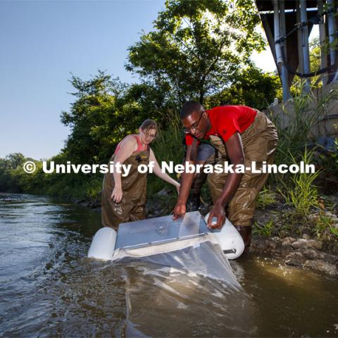 Meredith Sutton, graduate student in environmental engineering, McNair scholar Seth Caines, and summer research scholar Moriah Brown from Howard University retrieve a floating sieve to sample water from the Elkhorn River. They are working with Professor Shannon Bartlet-Hunt researching textiles as a source of microplastic fibers to Nebraska streams. July 2, 2021. Photo by Craig Chandler / University Communication.