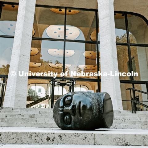 The Fallen Dreamer head sculpture lays on the front steps of the Sheldon Memorial Art Gallery on City Campus. July 21, 2021. Photo by Katie Black / University Communication.