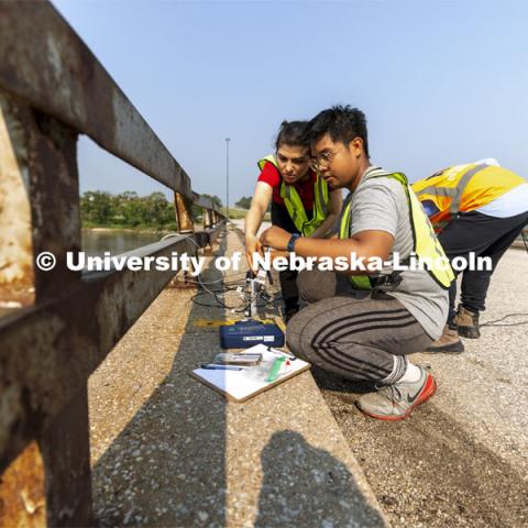 Mitra Nasimi and Awg Ku Ahmad Hashim Bin connect a replacement cable for the bridge sensors before testing began on the Platte River bridge. NOBL, the Nebraska Outdoor Bridge Lab as part of the College of Engineering is turning two bridge sites (for a total of three bridges) into a national research and educational facility for bridge health and testing. This bridge is across the Platte River on Highway 92 between Yutan and Omaha. August 9, 2021. Photo by Craig Chandler / University Communication.