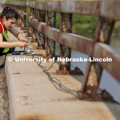Mitra Nasimi connects a replacement cable for the bridge sensors before testing began on the Platte River bridge. NOBL, the Nebraska Outdoor Bridge Lab as part of the College of Engineering is turning two bridge sites (for a total of three bridges) into a national research and educational facility for bridge health and testing. This bridge is across the Platte River on Highway 92 between Yutan and Omaha. August 9, 2021. Photo by Craig Chandler / University Communication.