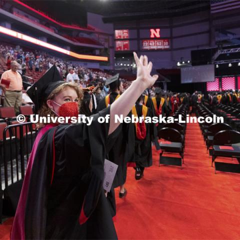 Emma Loberg waves to family and friends as the soon-to-be speech-language pathology masters degree recipient enters Pinnacle Bank Arena. Summer Graduate Commencement at Pinnacle Bank Arena. August 13, 2021. Photo by Craig Chandler / University Communication.