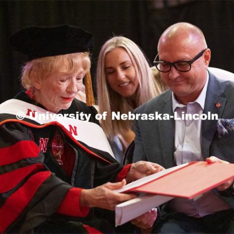 Leta Powell Drake, local television pioneer and Husker alumna, looks over her honorary Doctor of Humane Letters presented to her during the undergraduate ceremony. Her son, Aaron Drake, holds the degree while one of her granddaughters, Sierra, looks in. Undergraduate Commencement at Pinnacle Bank Arena. August 14, 2021. Photo by Craig Chandler / University Communication.