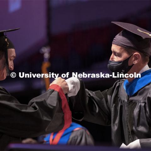 Daniel Linzell, associate dean for graduate and international programs in the College of Engineering and Leslie D. Martin Professor of Civil and Environmental Engineering, fist bumps an engineering graduate as he hands out diplomas. Undergraduate Commencement at Pinnacle Bank Arena. August 14, 2021. Photo by Craig Chandler / University Communication.