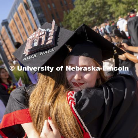 One last hug for 2020 architecture graduates Leia Farrens and Margaret Gies. Gies decorated her mortar board with a rendering of Architecture Hall. Undergraduate Commencement at Pinnacle Bank Arena. August 14, 2021. Photo by Craig Chandler / University Communication.