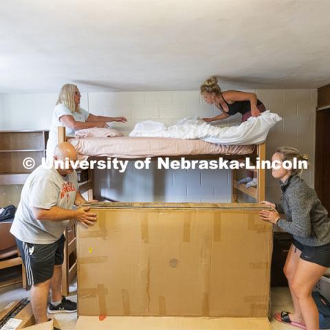 Family teamwork as Sophia Todora of Roscoe, IL, upper right, makes her bed with the help of her mom, Krissy. Her dad, Tony, and her sister, Ava, who is a UNL senior, wrestle with the futon box. Todora is an early move-in for sorority rush. Early arrival move-in for sorority rush, First Husker and Emerging Leaders. August 15, 2021. Photo by Craig Chandler / University Communication.